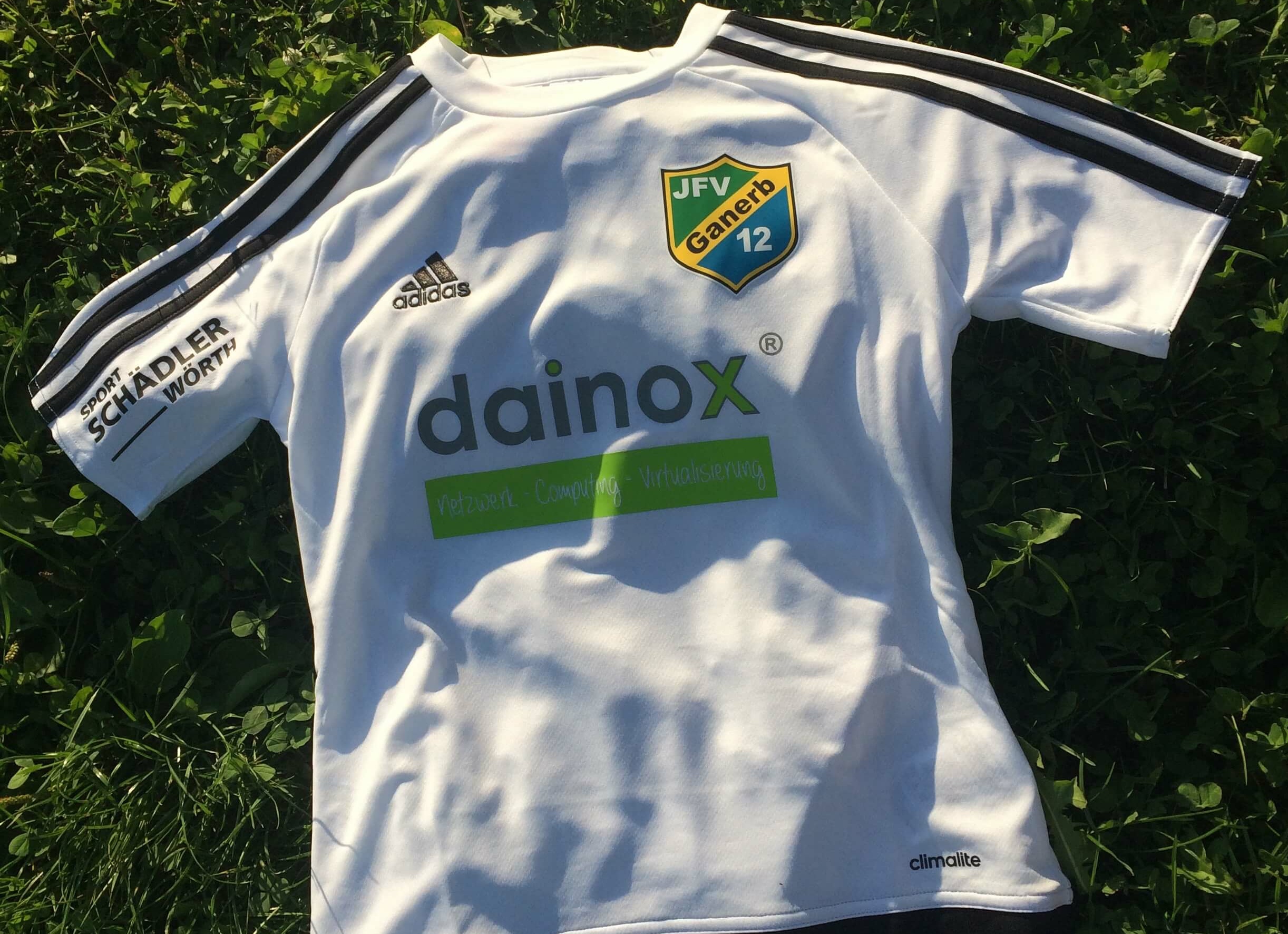 weißes dainox Trikot Fußball liegt auf grünem Rasen