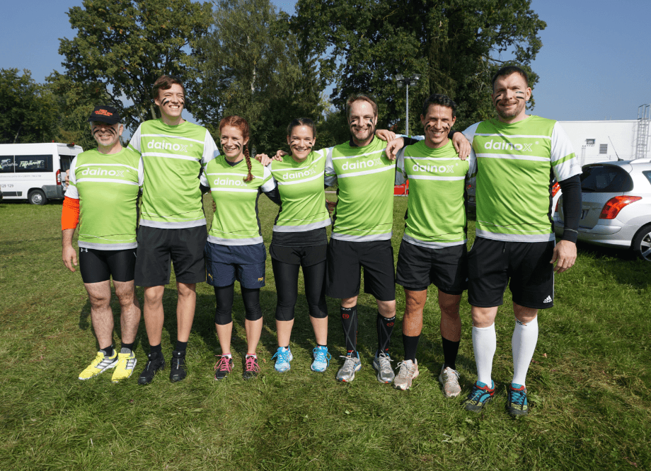 Gruppe von Kollegen mit grünem dainox-Trikots, das an einem Tough-Mudder Lauf teilnimmt. 